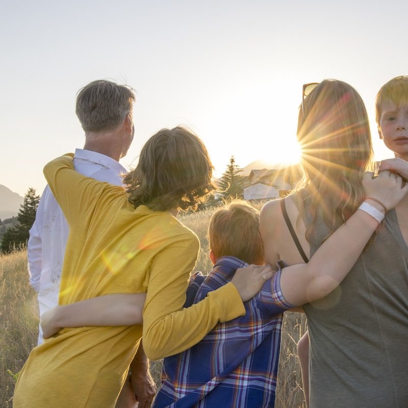 Young family in mountain meadow at sunset